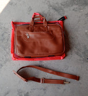 Faux leather messenger bag open with a laptop and other daily essentials neatly arranged inside.