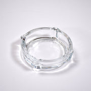 Clear glass ashtray featuring a classic round shape and convenient cigarette slots.