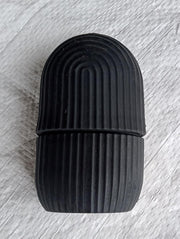 Black face ice roller placed on a textured grey cloth, showing its sleek design.