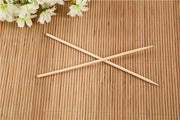 A hand holding a bamboo BBQ skewer with various ingredients for grilling.