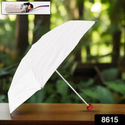 A white umbrella with a red handle is open on a wooden table, with a small inset showing it folded.